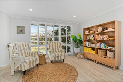 a living room with two chairs and a book shelf at Loganberry House - A Highlands home away from home in Bowral