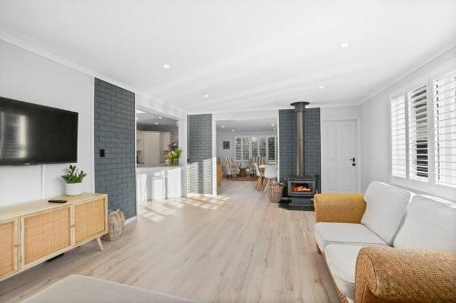 a living room with a white couch and a tv at Loganberry House - A Highlands home away from home in Bowral