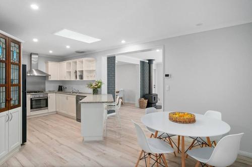 a kitchen and dining room with a white table and chairs at Loganberry House - A Highlands home away from home in Bowral