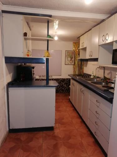 eine Küche mit weißen Schränken und schwarzen Arbeitsplatten in der Unterkunft SE ARRIENDA 1 HABITACION CASA HUECHURABA, Villa Las Bandurrias in Santiago