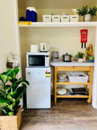 a kitchen with a microwave on top of a refrigerator at Tropical Suite PRIVATE CENTRAL BUDDINA STYLE by Custom Bnb Hosting in Buddina