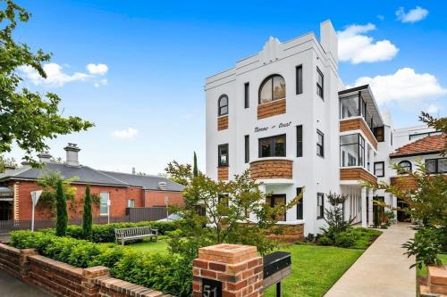 a white building with a courtyard in front of houses at A1 Art Deco 2 Bedroom Apt Sleeps 5 Nimmo1 in Melbourne