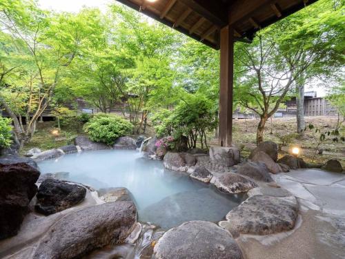 a pool of water with rocks in a yard at 天空の湯屋 山荘 華柚 in Oguni