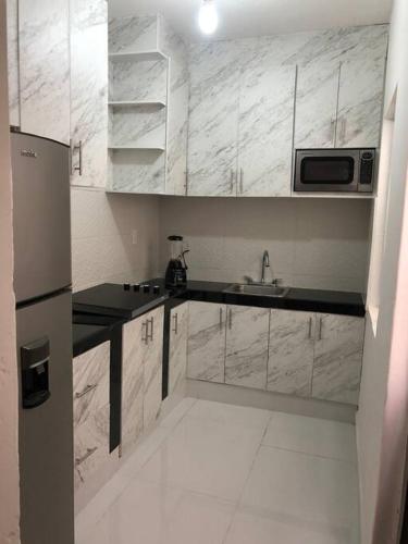 a white kitchen with a sink and a microwave at casa jireh in Santa Cruz Huatulco