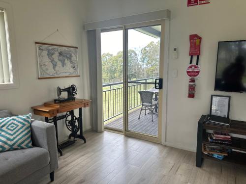 a living room with a sliding glass door with a balcony at Blueberry Hills On Comleroy Farmstay - Self-Contained Cottages in Kurrajong