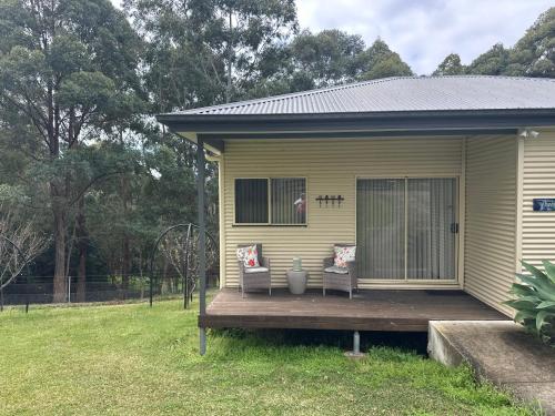 a yellow house with two chairs on a deck at Blueberry Hills On Comleroy Farmstay - Self-Contained Cottages in Kurrajong