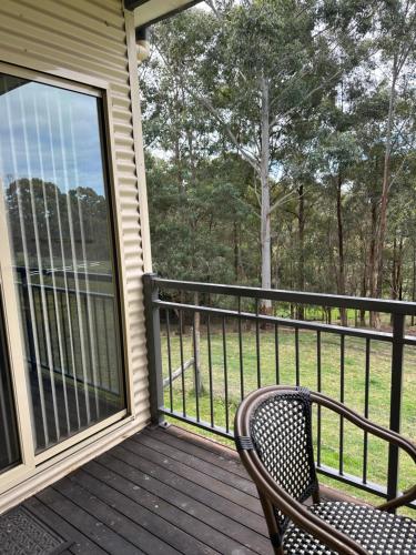 a balcony with a chair and a view of the woods at Blueberry Hills On Comleroy Farmstay - Self-Contained Cottages in Kurrajong