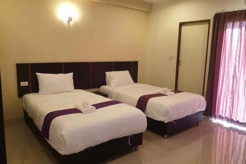 two beds in a hotel room with towels on them at La VIVA Hotel in Buriram