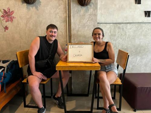 a man and a woman sitting at a table with a box at Doze Hostel in Chiang Mai