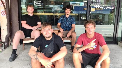 four men sitting on chairs in front of a store at Doze Hostel in Chiang Mai