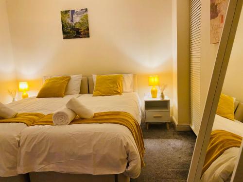 a bedroom with a large bed with yellow pillows at GB Relocations Ltd - Award Winning Merridale Executive Apartment, Free Parking, Free WiFi, Free Netflix in Wolverhampton
