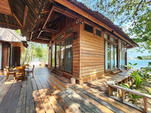 a wooden house with a table and chairs on a deck at Full Moon Island Resort in Kaoh Sdach