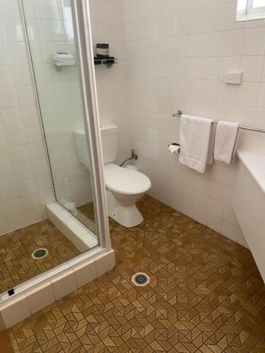 a bathroom with a toilet and a glass shower at Buckaroo Motor Inn in Warwick