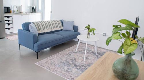 a living room with a blue couch and a table at Casita Amarilla By Stay Here Pr in San Juan