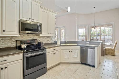 a kitchen with white cabinets and a stove top oven at Luxury Heated Pool Home, Hot tub, King bed suite in Lakeland