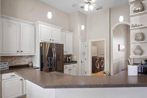 a kitchen with white cabinets and a stainless steel refrigerator at Luxury Heated Pool Home, Hot tub, King bed suite in Lakeland