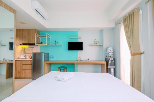 a bedroom with a bed and a desk and a television at Homey and Simply Look Studio Room at Bogor Icon Apartment By Travelio in Bogor