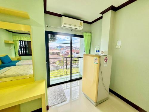 a room with a refrigerator and a bedroom with a balcony at โรงแรมกาญจนาสกลนคร in Sakon Nakhon