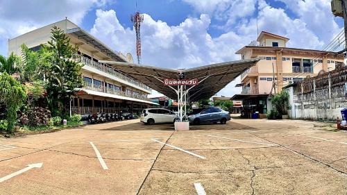 a parking lot with cars parked in front of a building at โรงแรมกาญจนาสกลนคร in Sakon Nakhon