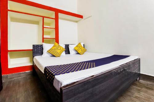 a bedroom with a bed with yellow and blue pillows at Hotel O Tirupati Guest House in Gwalior