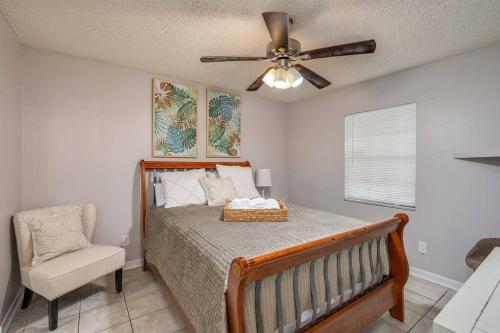 1 dormitorio con 1 cama con ventilador de techo y silla en King Bed Suite, Fireside Hot Tub, Gameroom, en Auburndale