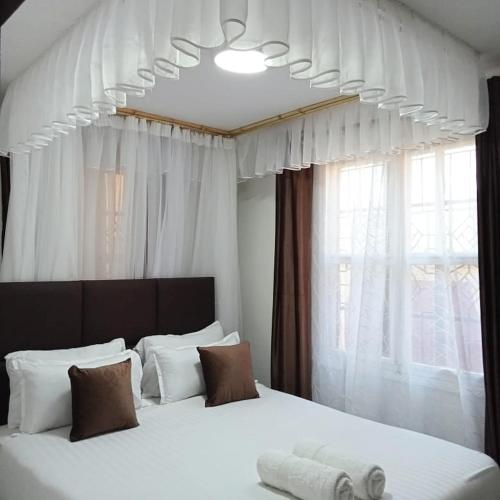 a bedroom with a large white bed with a window at Sofitel Executive 4 bedrooms Milimani in Kisumu
