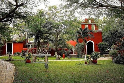 a red house with a bench in a yard at Hacienda Santa Cruz Merida in Mérida