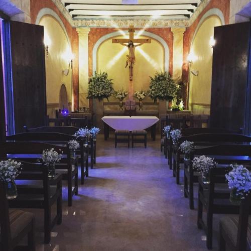 a altar in a church with chairs and a cross at Hacienda Santa Cruz Merida in Mérida