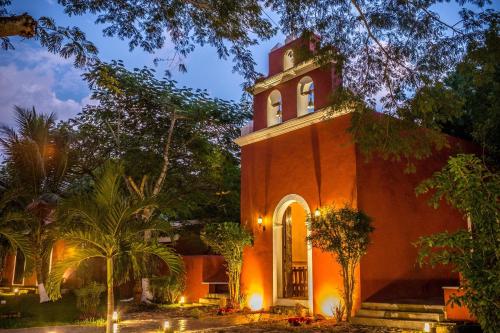 a church with a clock tower on top of it at Hacienda Santa Cruz Merida in Mérida