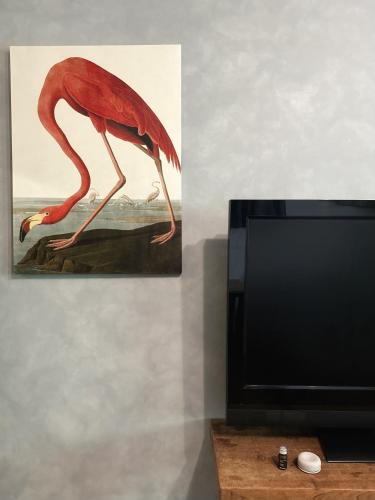 a painting of a flamingo next to a tv at Dulan The Travel Bug Bistro Inn in Donghe