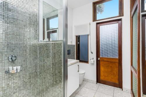 a bathroom with a shower and a toilet and a glass door at Shambhala @ Byron in Byron Bay