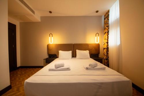 a bedroom with a large white bed with towels on it at V Center Hotel in Trabzon