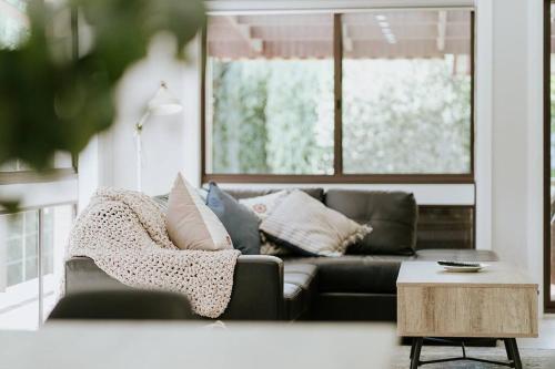 a black couch in a living room with a window at Teds Place Close to Bowral Town in Bowral