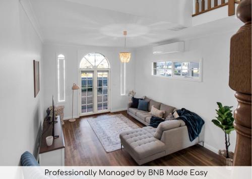 a living room with a couch and a tv at Parkham - CBD, Elegant Townhouse in Wagga Wagga