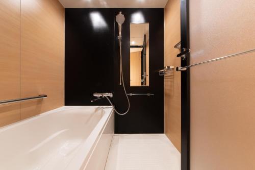 a bathroom with a tub and a black wall at Hotel Vista Fukuoka Nakasu-Kawabata in Fukuoka