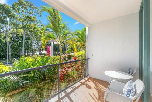 Un balcón con mesa y sillas y palmeras. en Shelly Bay Resort, en Hervey Bay