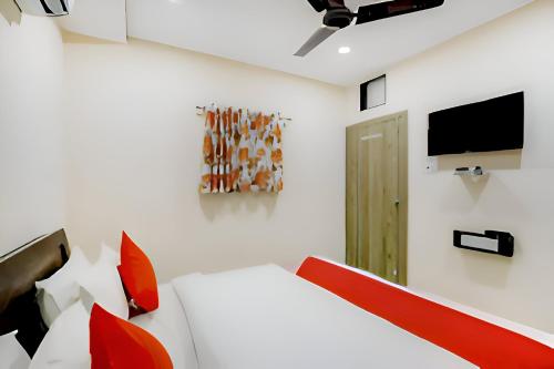 a bedroom with a bed and a tv on the wall at Hotel Blue Leaf in Rajkot