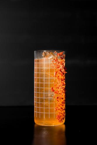 a glass jar filled with orange liquid on a table at The Reverie Saigon Residential Suites in Ho Chi Minh City