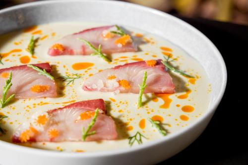 a bowl of soup with ham and vegetables in it at The Reverie Saigon Residential Suites in Ho Chi Minh City