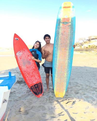 a man and woman standing on the beach with surfboards at Casa Tarantini in Lobitos