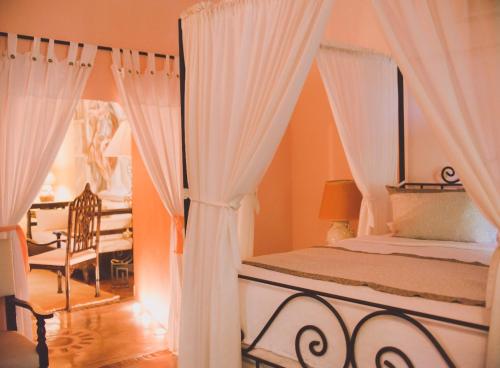 a bedroom with a bed with white curtains and a chair at Hacienda Santa Cruz Merida in Mérida