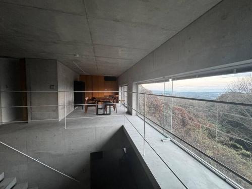 a room with a balcony with a table and a large window at SENSE Beppuwan in Hiji