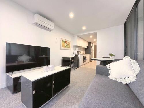 a living room with a couch and a large tv at Central located 1Bedroom Apartment in Woden By Serain Residences in Phillip