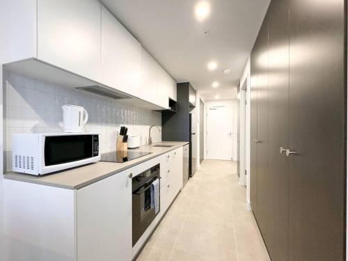 a kitchen with white cabinets and a microwave at Central located 1Bedroom Apartment in Woden By Serain Residences in Phillip