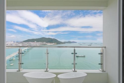 a balcony with two chairs and a view of the water at Elmomento Songdo in Busan