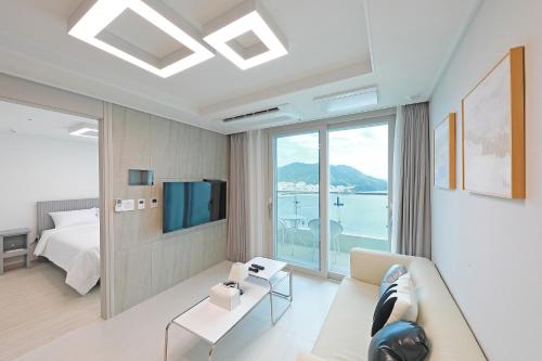 a living room with a couch and a bed and a window at Elmomento Songdo in Busan