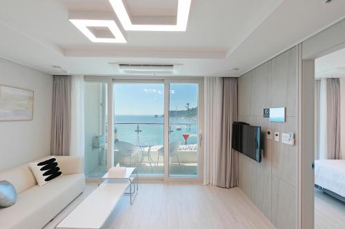 a living room with a couch and a view of the ocean at Elmomento Songdo in Busan