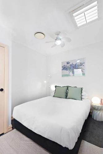 a bedroom with a white bed with two green pillows at Fitzroy Private Rooms - 132 Nicholson Homestay in Melbourne