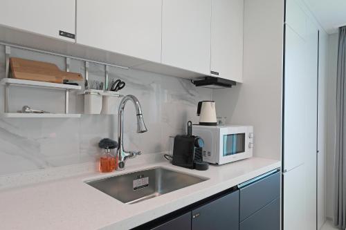 a kitchen with a sink and a microwave at Elmomento Songdo in Busan