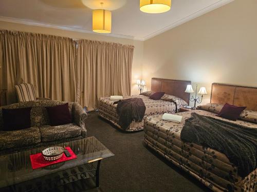 a hotel room with two beds and a couch at Gateway Motor Inn in Masterton